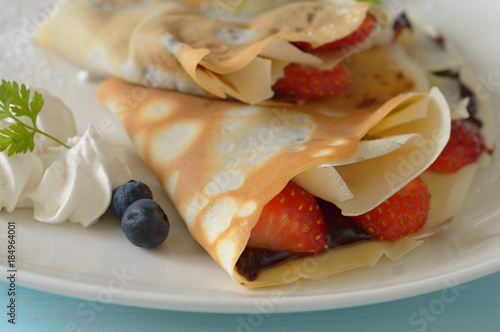 a plate of Japanese crepe with chocolate cream and fresh strawberries