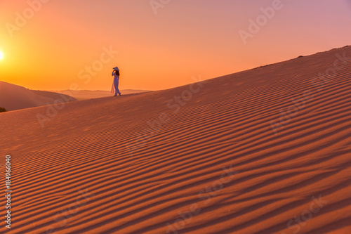 Obraz na płótnie Woman walk alone on The red sand dunes in MUI NE, Vietnam is popular travel destination with long coastline, silver sand and huge sea waves