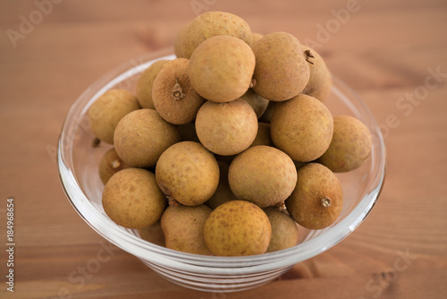 Bowl filled with an heap Dimocarpus Longan fruit on wooden background