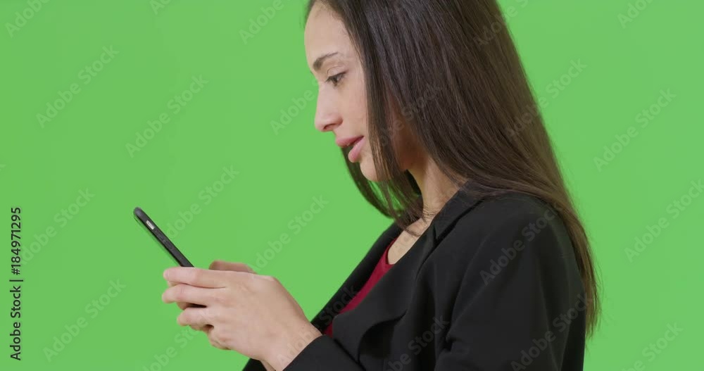 A Hispanic office worker texts on her mobile phone on green screen. On green screen to be keyed or composited. A Hispanic office worker texts on her mobile phone on green screen. On green screen to be keyed or composited.