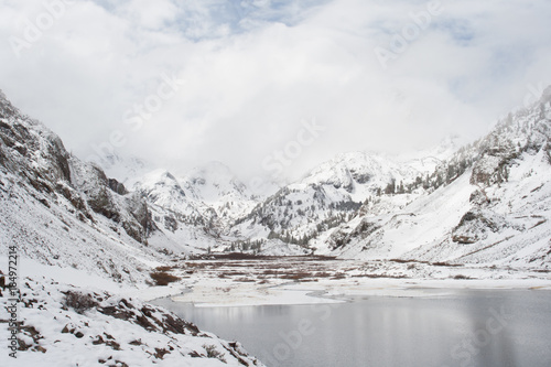 Landscape view of snow covered mountains with a lake in the foreground. 