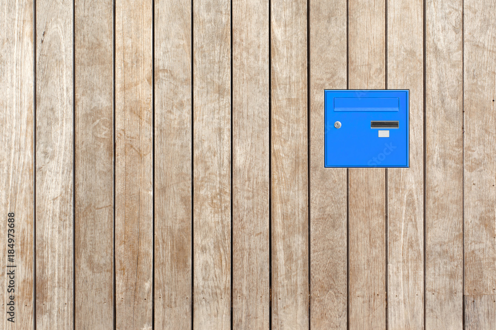boîte aux lettres bleue sur fond palissade bois 