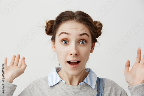 Fotografie Close up surprised girl with european appearance looking on camera with open mouth throwing up hands