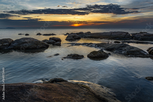 Rocks in the sea with sunset sky. © arnuphapy