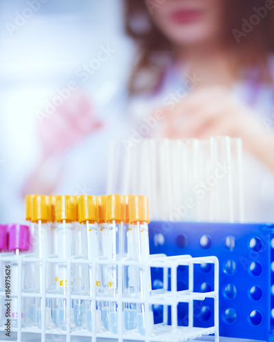 Woman researcher is surrounded by medical vials and flasks, isolated on white.