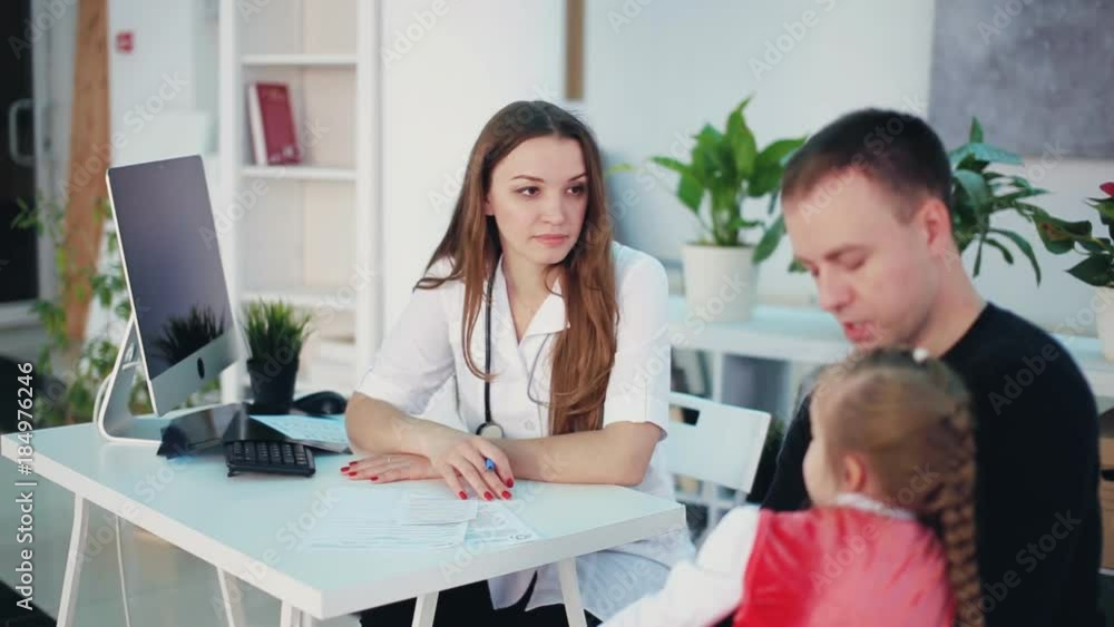 female pediatrician smiling and talks to a little girl female pediatrician smiling and talks to a little girl