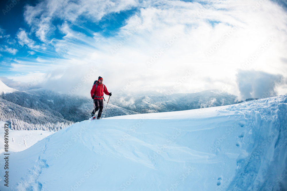 A man in snowshoes in the mountains in the winter.