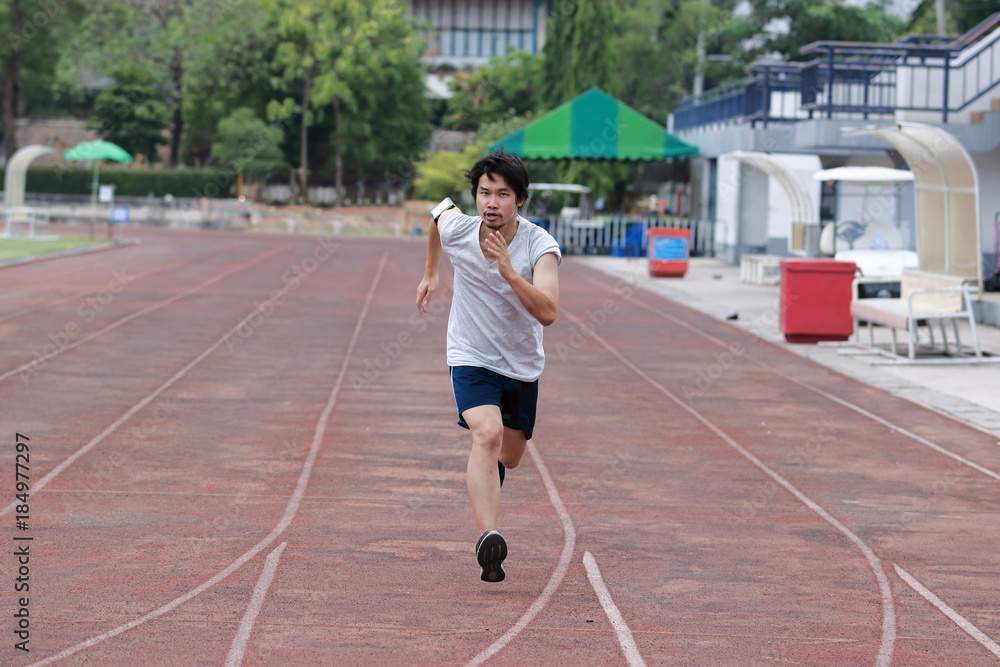 Runner athlete man running on the trackrace in stadium . Jogging for healthy concept