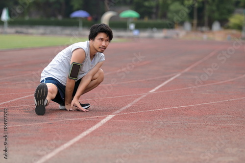 Healthy young Asian runner man warming up before run on track in the stadium © tuaindeed