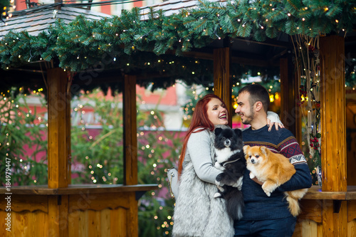 Wallpaper Mural Christmas holidays. Young couple on the Christmas bazaar with pets. Torontodigital.ca