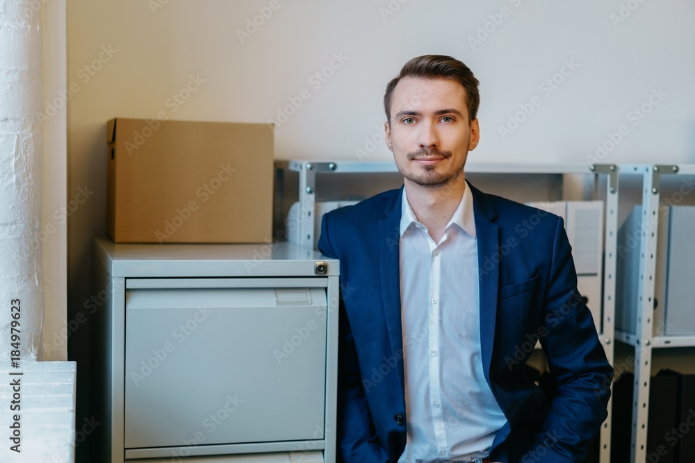 Fototapeta premium Man leaning against storage cabinet in office