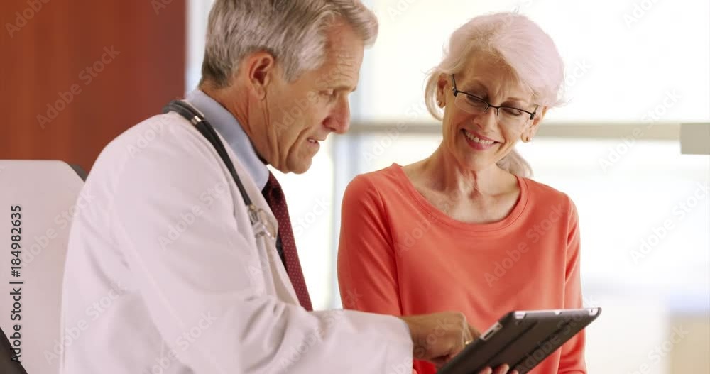 Friendly senior doctor talking with elderly woman patient in the office Friendly senior doctor talking with elderly woman patient in the office