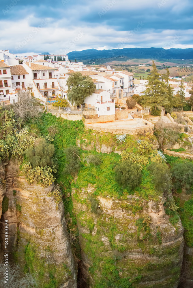 A view to El Tajo Gorge Canyon, white traditional andalusian houses and mountains in Ronda, one of the most famous white villages (pueblos blancos) in Malaga province, Andalusia, Spain.