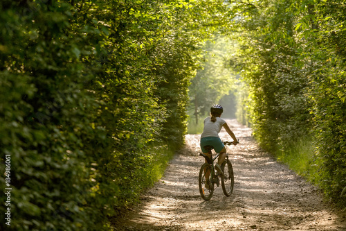 Woman rides bicycle in the beautiful green forest