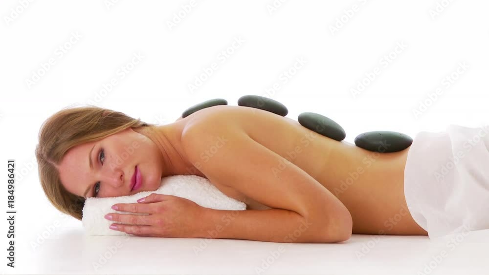 Woman laying facedown at spa with hot rocks on back Woman laying facedown at spa with hot rocks on back