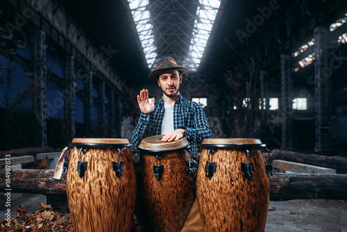 Photography Drummer plays on african drums in factory shop