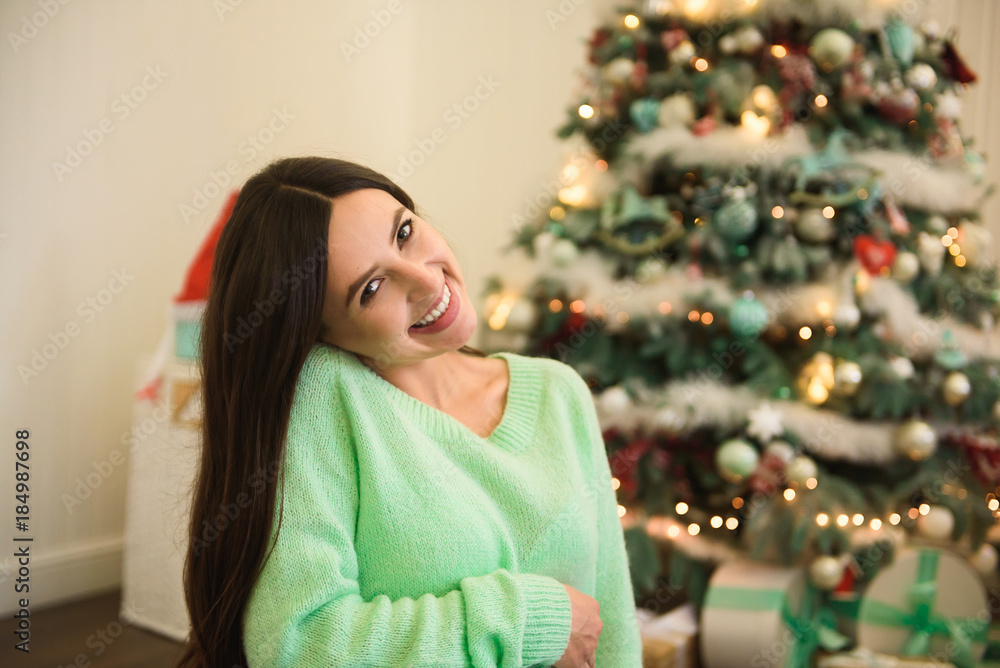 Holidays, celebration and people concept - young woman over christmas interior background.