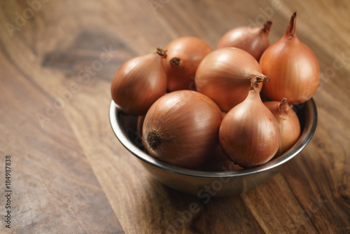 brown onions in steel bowl on old wood table
