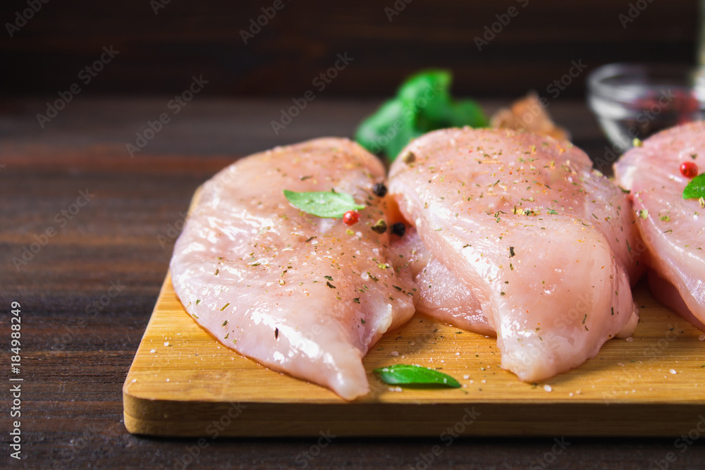 Raw chicken fillets on a cutting board against the background of a wooden table. Meat ingredients for cooking.