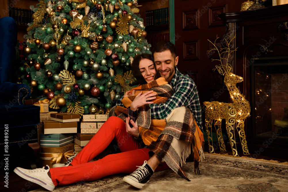 Young couple with gifts near Christmas tree
