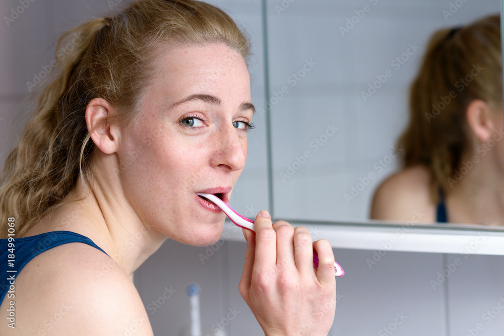 Beautiful woman smiling while brushing her teeth Beautiful woman smiling while brushing her teeth