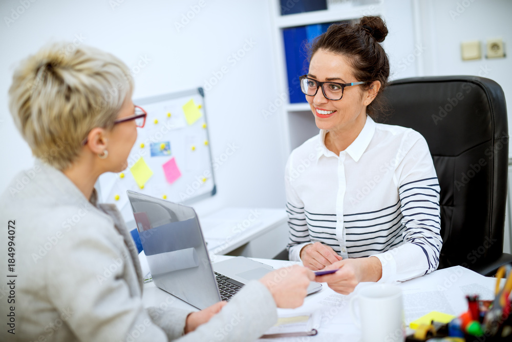 Obraz premium Close up of focused professional satisfied woman worker taking bank card from female customer in the office.