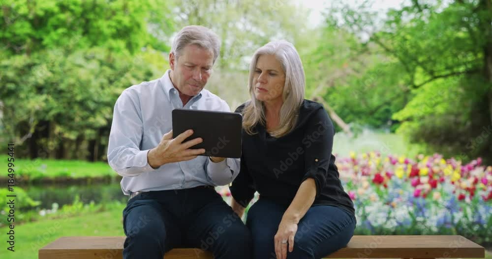 White male and female seniors use tablet to find directions from park