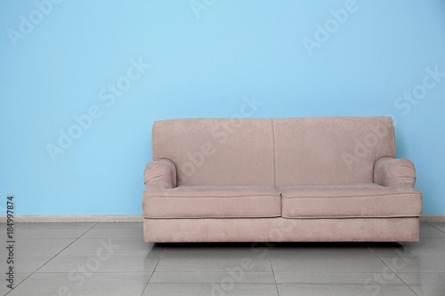 Stylish sofa near color wall indoors