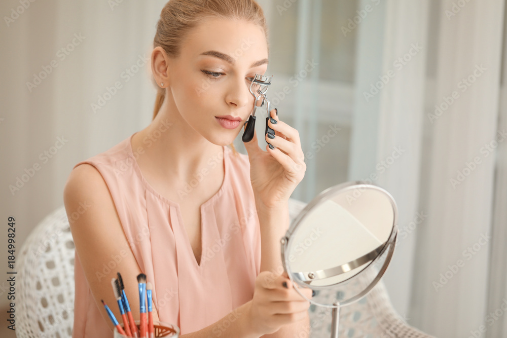 Beautiful young woman using eyelash curler at home Beautiful young woman using eyelash curler at home
