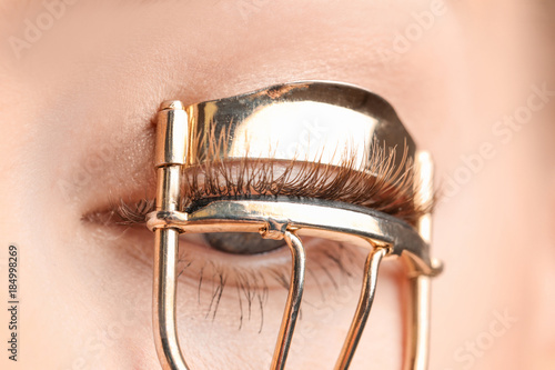 Woman using eyelash curler,...