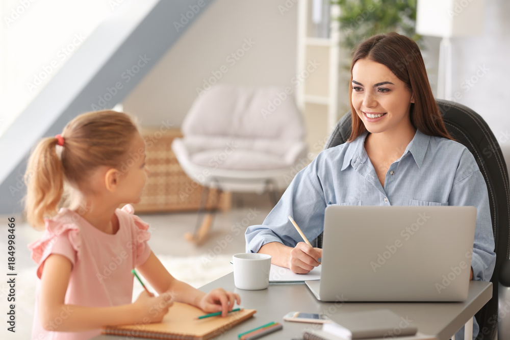 Busy young woman with daughter in home office Busy young woman with daughter in home office