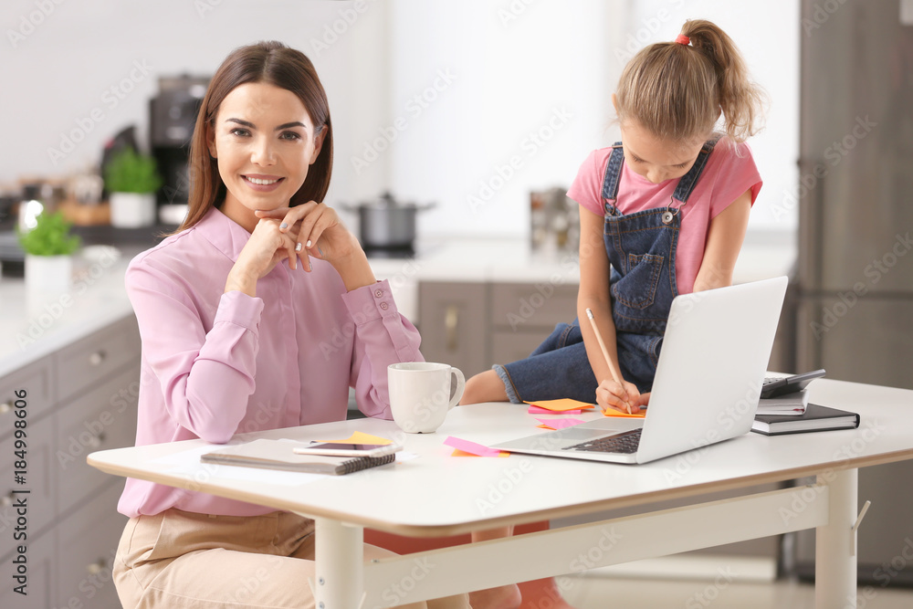 Busy young woman with daughter in home office Busy young woman with daughter in home office