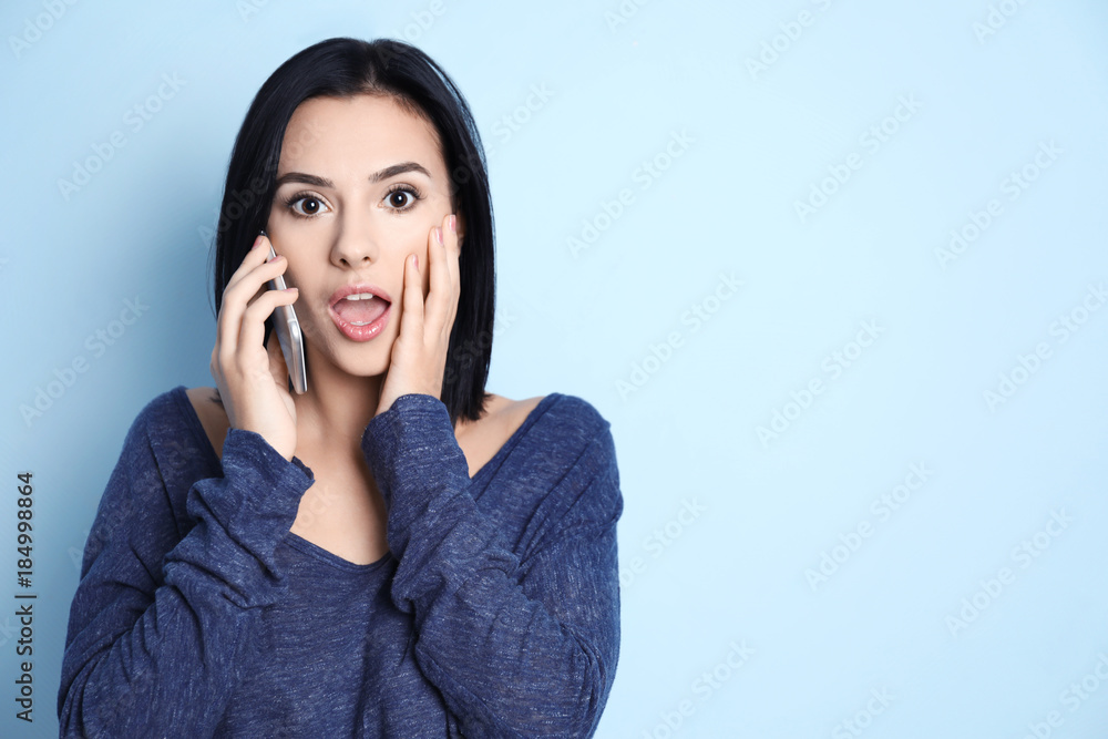 Emotional young woman speaking by mobile phone on color background Emotional young woman speaking by mobile phone on color background
