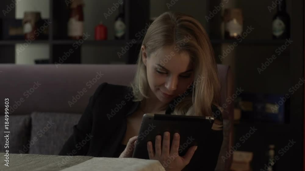 Beautiful woman typing message on screen tablet pc sitting at couch in cafe Beautiful woman typing message on screen tablet pc sitting at couch in cafe
