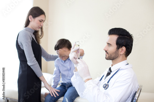 Doctor preparing injection kid at hospital. Kid scary needle when looking doctor hold. People with medical concept.
