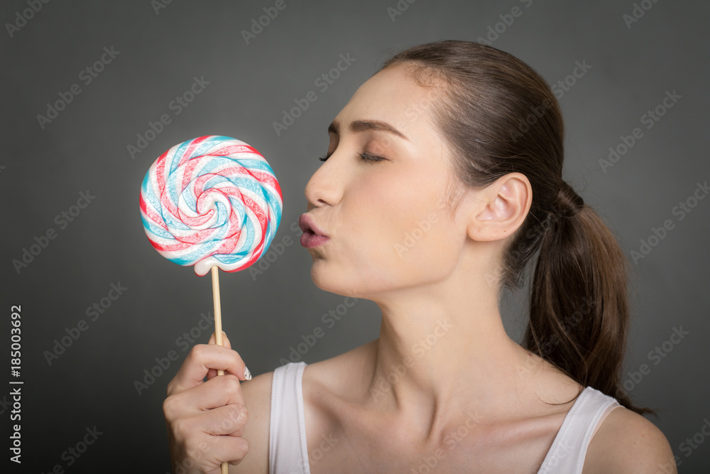 Portrait of happyBeautiful Woman holding lollypop. isolated on gray background