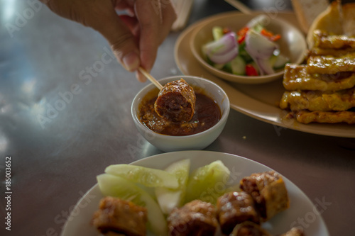 Dip the Deep Fried Crab and chicken meat roll (Hoi Jo) in sauce, southern style food of Thailand