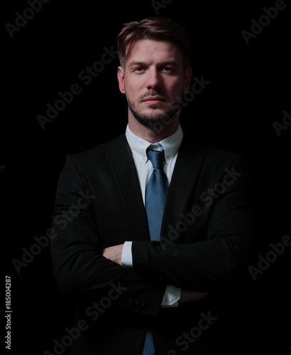 Handsome business man isolated on black with arms crossed