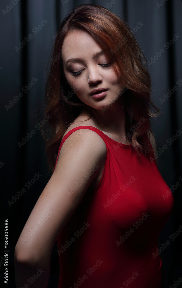 Charming brunette in a red dress posing on a black background. Charming brunette in a red dress posing on a black background.
