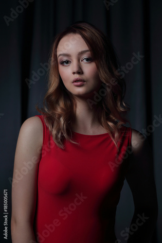 Charming brunette in a red dress posing on a black background.