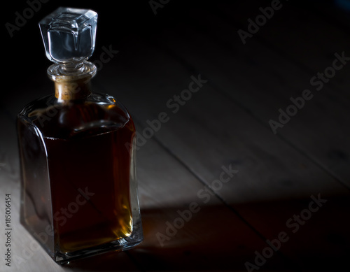 Whiskey/Rom/liquor in a vintage bottle being lidt from the side - casting colored light and shadows on wooden floor   boards