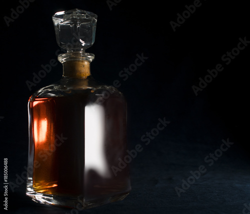 Whiskey/Rom/liquor in a vintage bottle pictured close up with a side light and dark blue velour