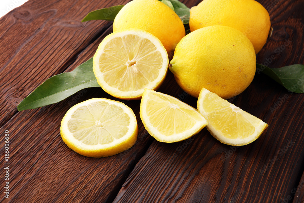 Pile of lemons with leaves on brown wooden table Pile of lemons with leaves on brown wooden table