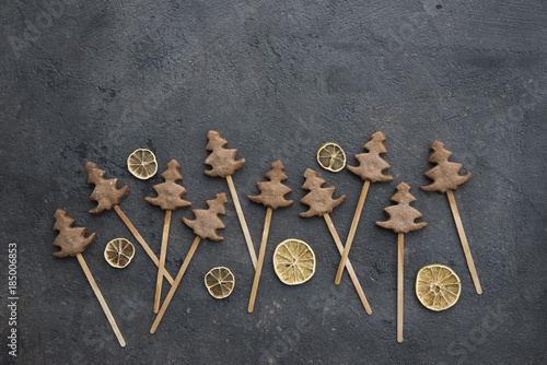 christmas cookies (in the form of Christmas trees) on sticks on a dark background