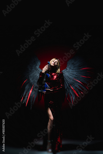 Female with big angel wings on black background.