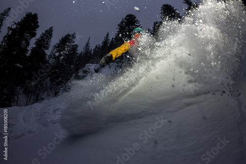 freerider snowboarder jumping at night with a springboard in the forest