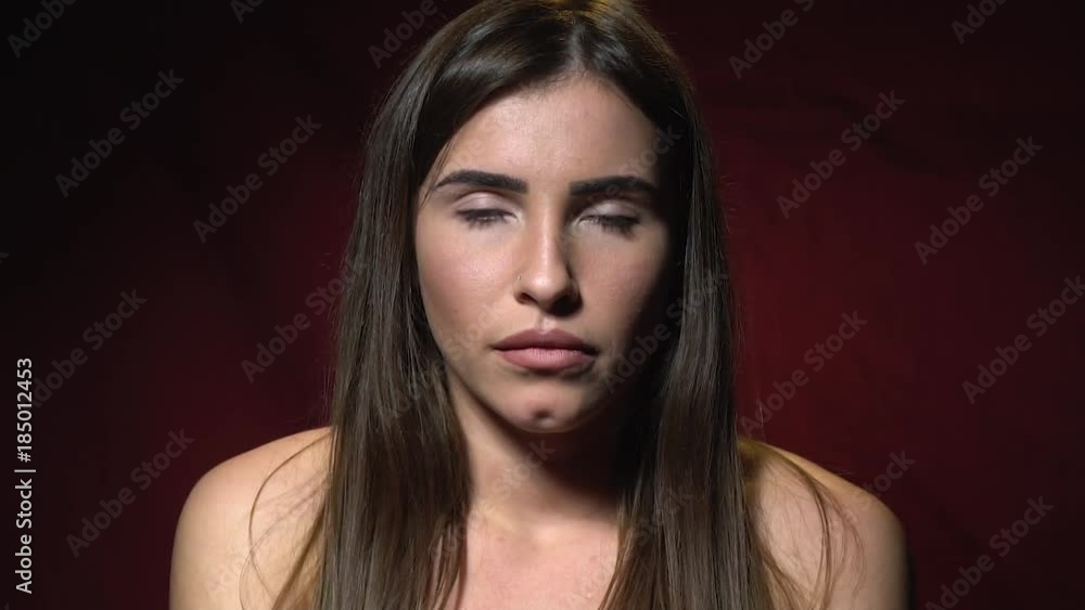 A beautiful brunette with a piercing in her nose is standing and sadly sighs A beautiful brunette with a piercing in her nose is standing and sadly sighs