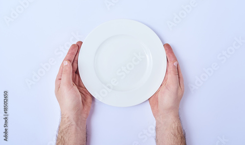 Empty round plate in man's hands isolated on white background