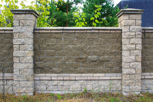 The texture of a stone fence with rectangular blocks and concrete seams.