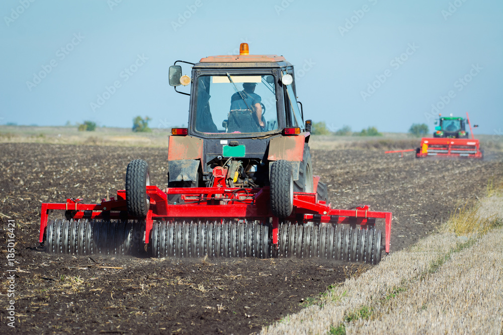 Fototapeta premium Tractor with a roller on the field at spring